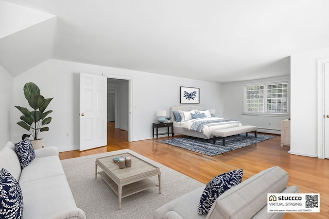 bedroom featuring light hardwood / wood-style flooring, lofted ceiling, and a baseboard radiator