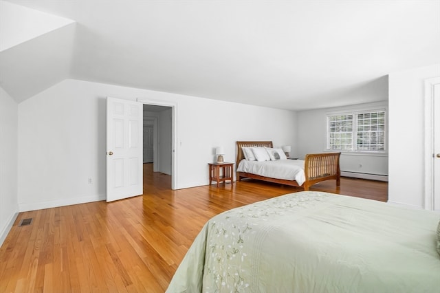 bedroom with lofted ceiling, light wood-type flooring, and baseboard heating