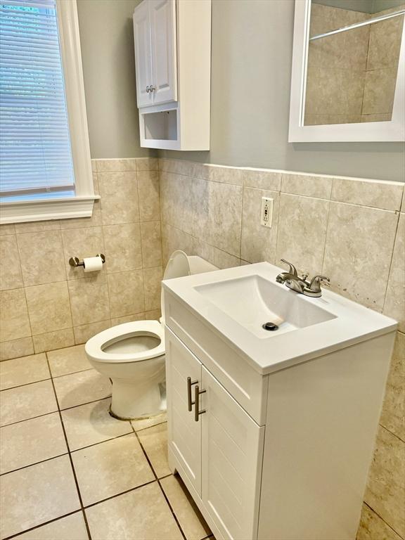 437 Ferry St Unit 1, Everett, MA 02149 - bathroom featuring tile walls, vanity, tile patterned flooring, and a wainscoted wall
