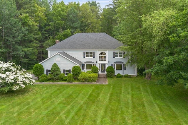 32 Twin Pond Ln, Sudbury, MA 01776 - colonial-style house featuring a front yard, a chimney, and a forest view