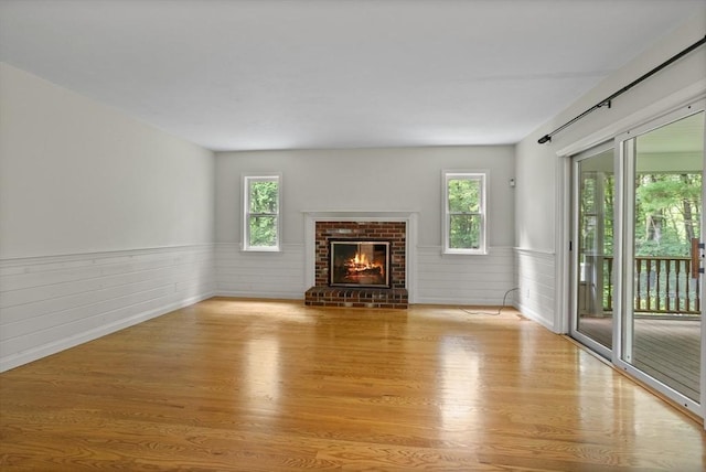 32 Twin Pond Ln, Sudbury, MA 01776 - unfurnished living room featuring wood finished floors, wainscoting, plenty of natural light, and a brick fireplace