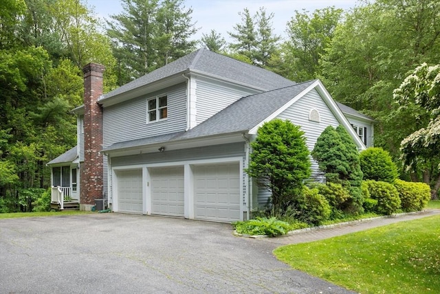 32 Twin Pond Ln, Sudbury, MA 01776 - view of property exterior with a chimney, a shingled roof, asphalt driveway, and view of scattered trees