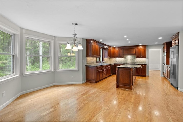 32 Twin Pond Ln, Sudbury, MA 01776 - kitchen featuring stainless steel appliances, a kitchen island, decorative backsplash, a chandelier, and light wood-style flooring