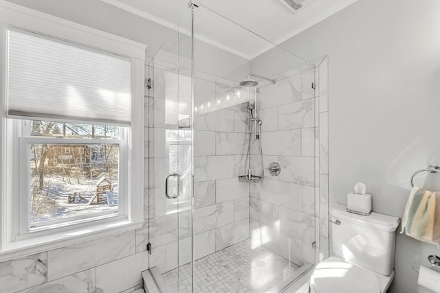 bathroom with a shower with door, crown molding, plenty of natural light, and toilet