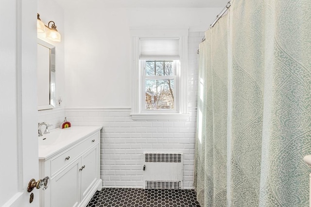 bathroom featuring vanity, radiator, and tile walls