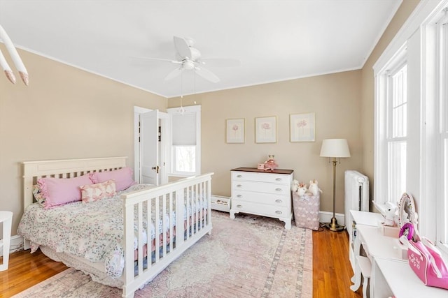 bedroom featuring radiator heating unit, ceiling fan, and light wood-type flooring