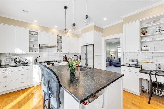 kitchen featuring a breakfast bar, white cabinetry, hanging light fixtures, high quality fridge, and an island with sink