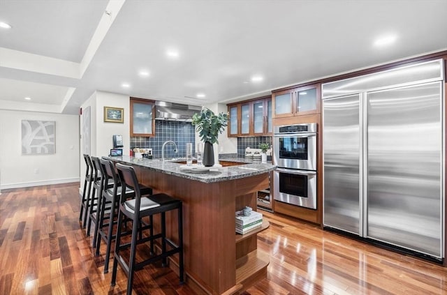 4 Battery Wharf Unit 4504, Boston, MA 02109 - kitchen featuring stainless steel appliances, backsplash, a kitchen breakfast bar, wood finished floors, and dark stone countertops