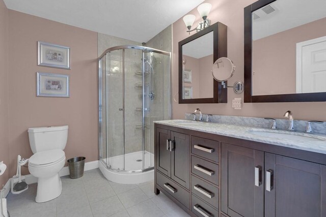 bathroom with tile patterned floors, vanity, toilet, and a shower with door