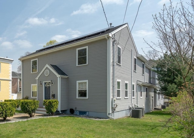 view of front of house featuring solar panels, central air condition unit, and a front yard