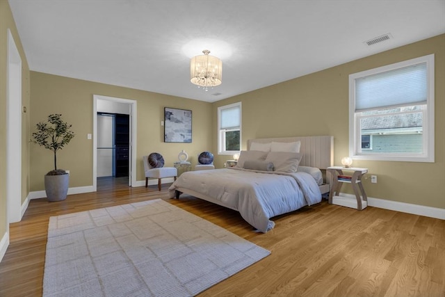 bedroom with light hardwood / wood-style flooring and a chandelier