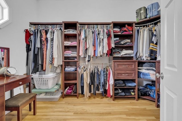 walk in closet with light hardwood / wood-style floors