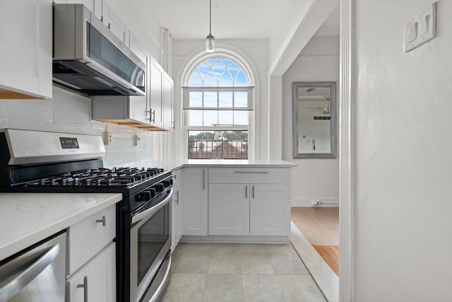 kitchen with stainless steel appliances, white cabinets, pendant lighting, and light stone counters