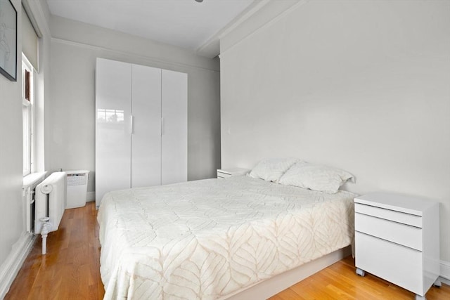 bedroom with radiator, a closet, and light hardwood / wood-style floors