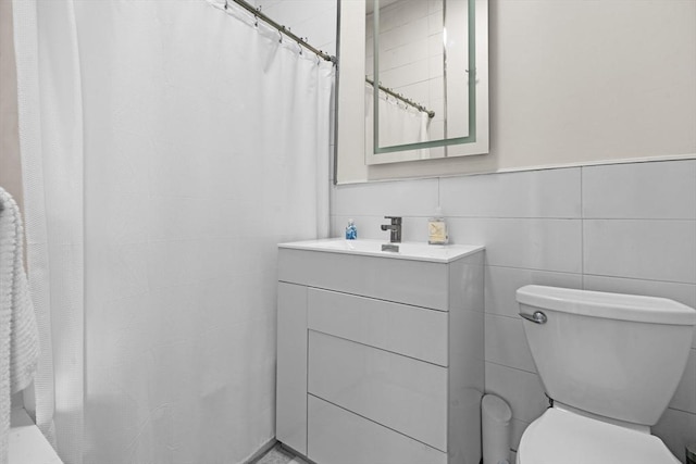 bathroom with tile walls, curtained shower, vanity, and toilet