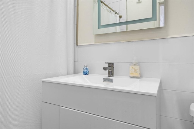 bathroom with decorative backsplash, vanity, and tile walls