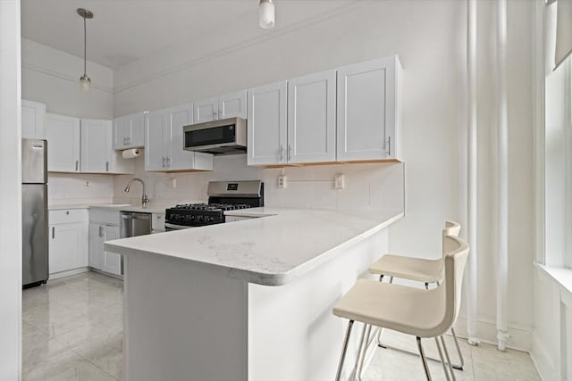 kitchen with appliances with stainless steel finishes, a breakfast bar, white cabinets, and kitchen peninsula