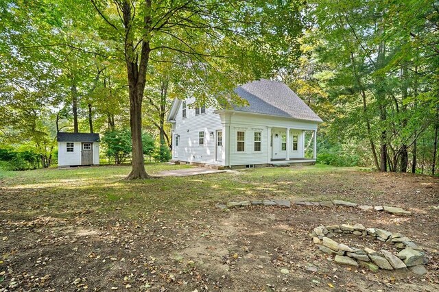 back of property with a storage unit and a fire pit