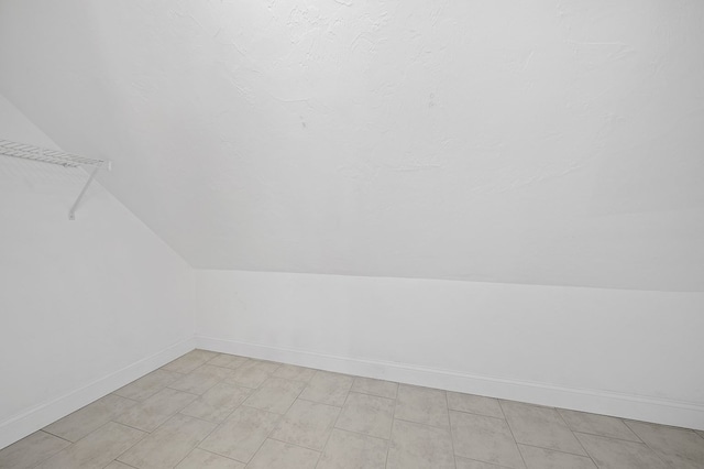 additional living space featuring light tile patterned floors and lofted ceiling