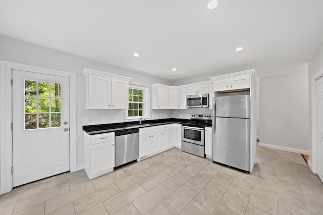 kitchen featuring light tile patterned flooring, appliances with stainless steel finishes, sink, and white cabinets