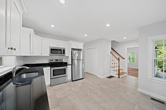 kitchen with sink, stainless steel appliances, white cabinetry, and light tile patterned floors