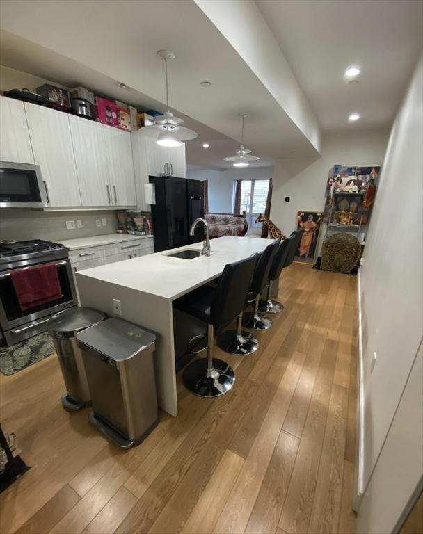 kitchen featuring sink, white cabinets, a kitchen bar, a kitchen island with sink, and stainless steel appliances