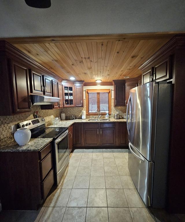 kitchen with decorative backsplash, appliances with stainless steel finishes, under cabinet range hood, a sink, and light tile patterned flooring