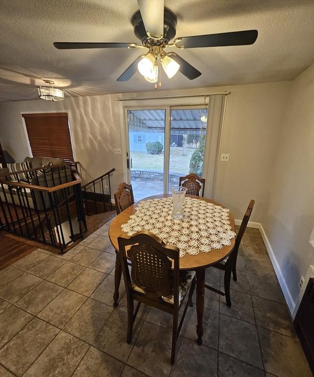 dining space featuring dark tile patterned flooring, a textured ceiling, and baseboards