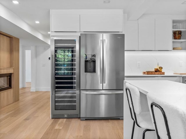 8 Wiswall Unit 8, Wellesley, MA 02482 - kitchen with stainless steel fridge, beverage cooler, open shelves, light wood-type flooring, and white cabinets