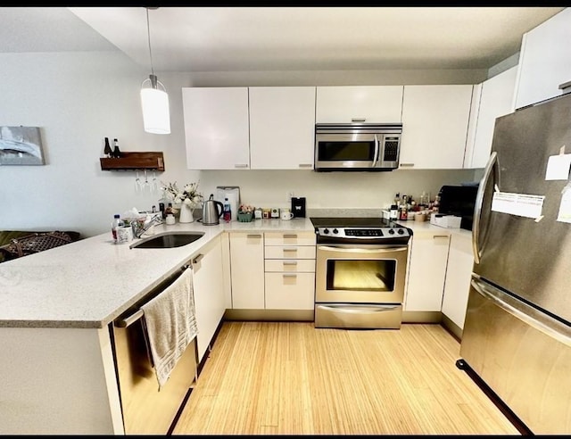 2 Earhart Unit 121, Cambridge, MA 02141 - kitchen with appliances with stainless steel finishes, a sink, a peninsula, and white cabinetry
