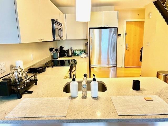 2 Earhart Unit 121, Cambridge, MA 02141 - kitchen featuring stainless steel appliances, white cabinetry, and light stone countertops