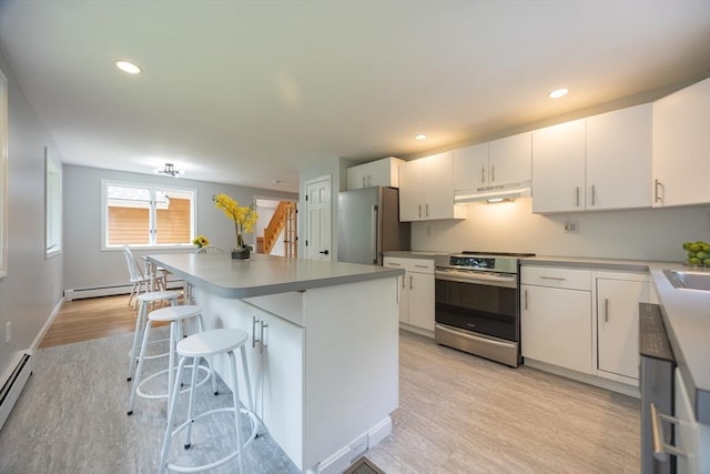 56 Burt St, Norton, MA 02766 - kitchen with stainless steel appliances, under cabinet range hood, light wood-style flooring, white cabinets, and a kitchen island