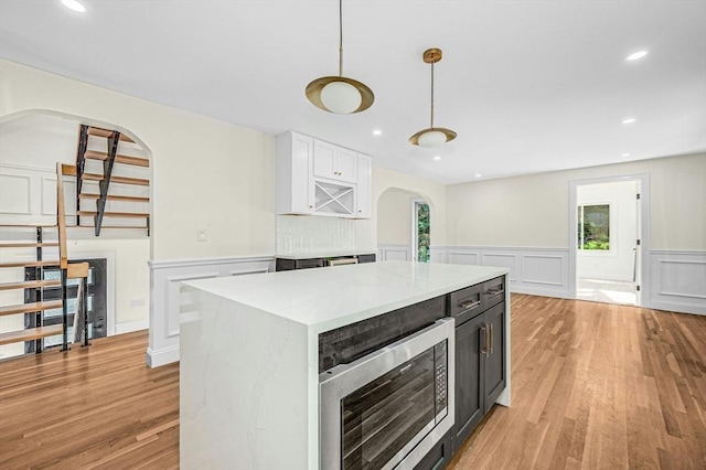 30 Twilight Dr, Foxboro, MA 02035 - kitchen with arched walkways, stainless steel microwave, wainscoting, a decorative wall, and white cabinets
