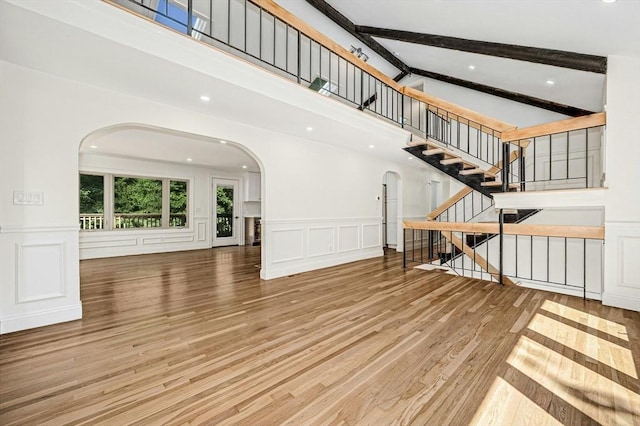 30 Twilight Dr, Foxboro, MA 02035 - unfurnished living room featuring arched walkways, a decorative wall, wood finished floors, a high ceiling, and stairs