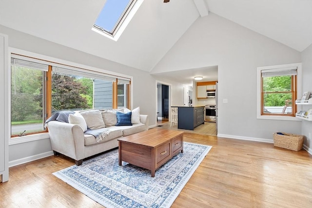 12 Billings St, Acton, MA 01720 - living area featuring high vaulted ceiling, baseboards, light wood-type flooring, a skylight, and beam ceiling