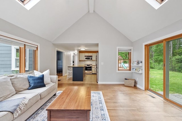 12 Billings St, Acton, MA 01720 - living area featuring high vaulted ceiling, light wood-style flooring, a skylight, beamed ceiling, and baseboards