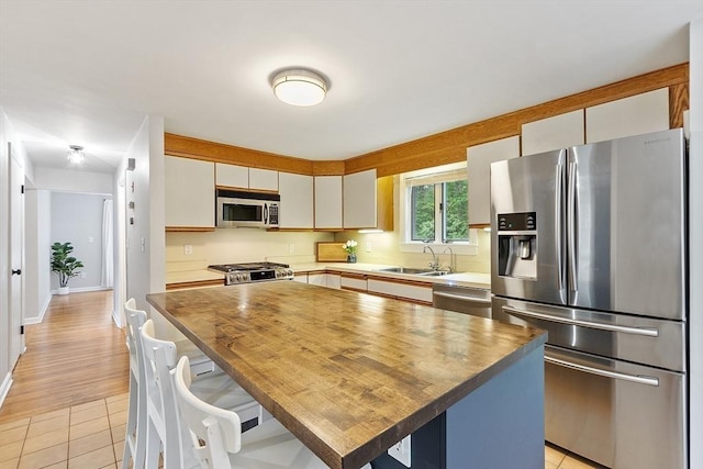 12 Billings St, Acton, MA 01720 - kitchen with stainless steel appliances, a sink, light tile patterned floors, a kitchen island, and butcher block counters