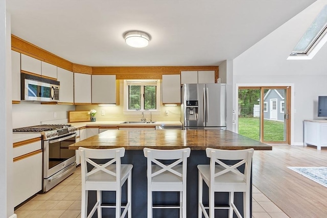 12 Billings St, Acton, MA 01720 - kitchen with appliances with stainless steel finishes, a sink, a kitchen breakfast bar, a skylight, and light tile patterned floors