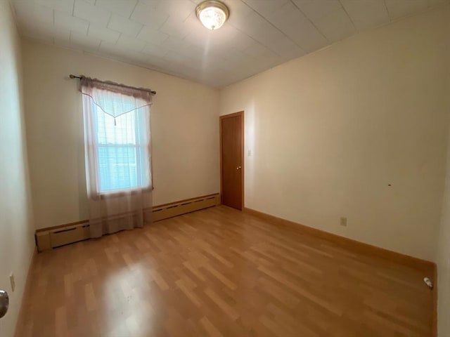 empty room with baseboards, a baseboard radiator, and light wood-type flooring