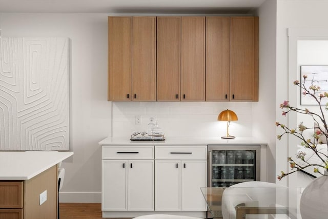 20 Audubon Way Unit 203, Canton, MA 02021 - kitchen featuring beverage cooler, light countertops, tasteful backsplash, wood finished floors, and white cabinets