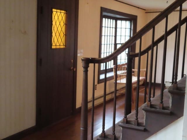 stairs featuring baseboards, baseboard heating, and wood finished floors