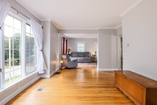 living room featuring crown molding, light hardwood / wood-style floors, and a wealth of natural light