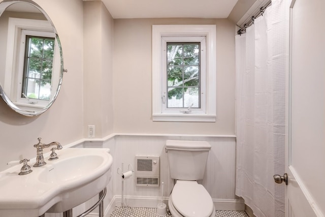 bathroom featuring sink, heating unit, toilet, and a wealth of natural light