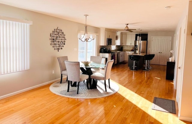 dining space with ceiling fan with notable chandelier and light wood-type flooring