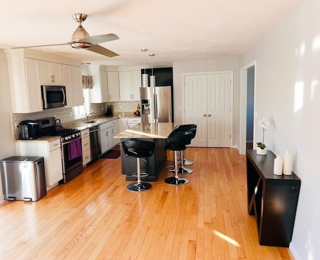 kitchen with stainless steel appliances, a center island, a breakfast bar area, and white cabinets