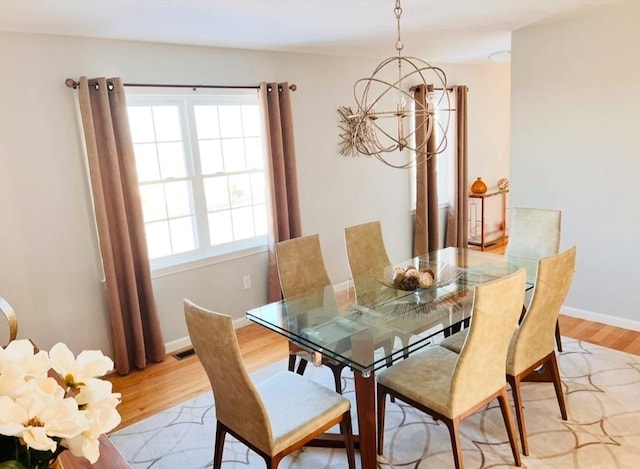 dining space with a notable chandelier and light hardwood / wood-style floors