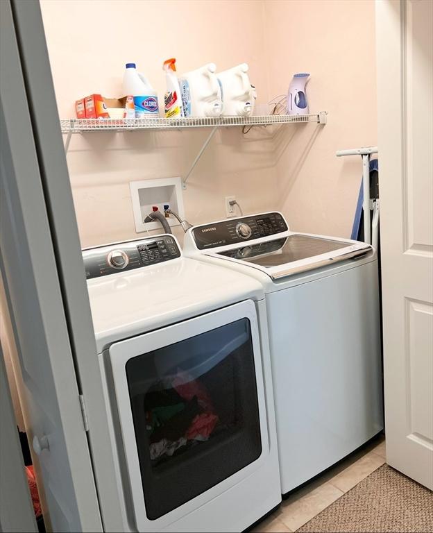 laundry area with separate washer and dryer and light tile patterned floors