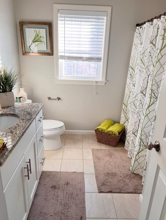 bathroom featuring vanity, a healthy amount of sunlight, tile patterned floors, and toilet