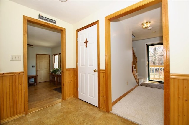 corridor featuring light colored carpet and wood walls