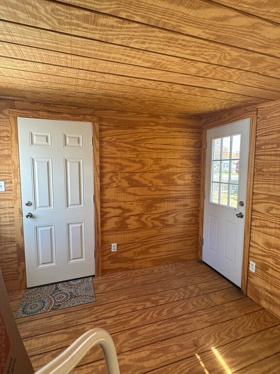 doorway with wood ceiling, wooden walls, and wood finished floors